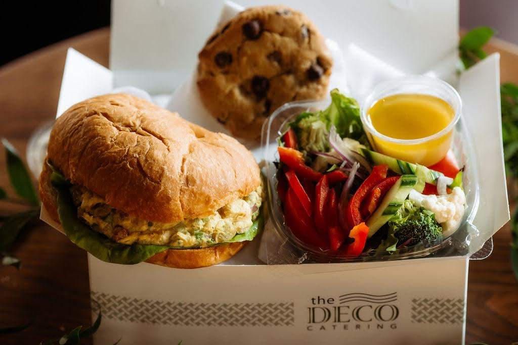 A boxed lunch with a sandwich, salad, and a cookie
